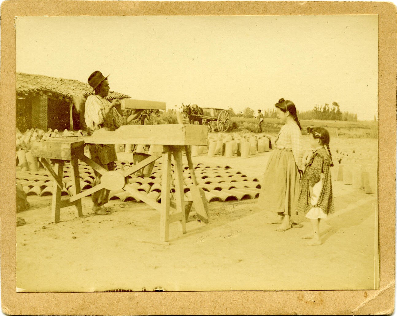 q.-Albañil haciendo teja con los galápagos. Niñas observando